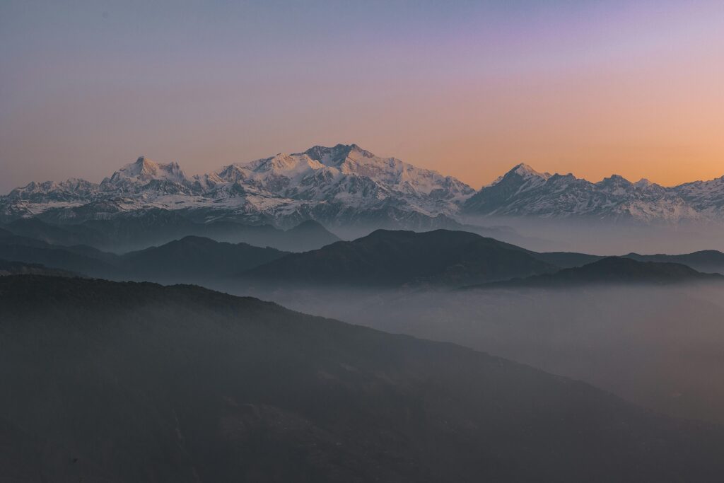 Beautiful sunrise view of the snow-covered Himalayas in Sikkip, India, with misty valleys and a scenic backdrop.