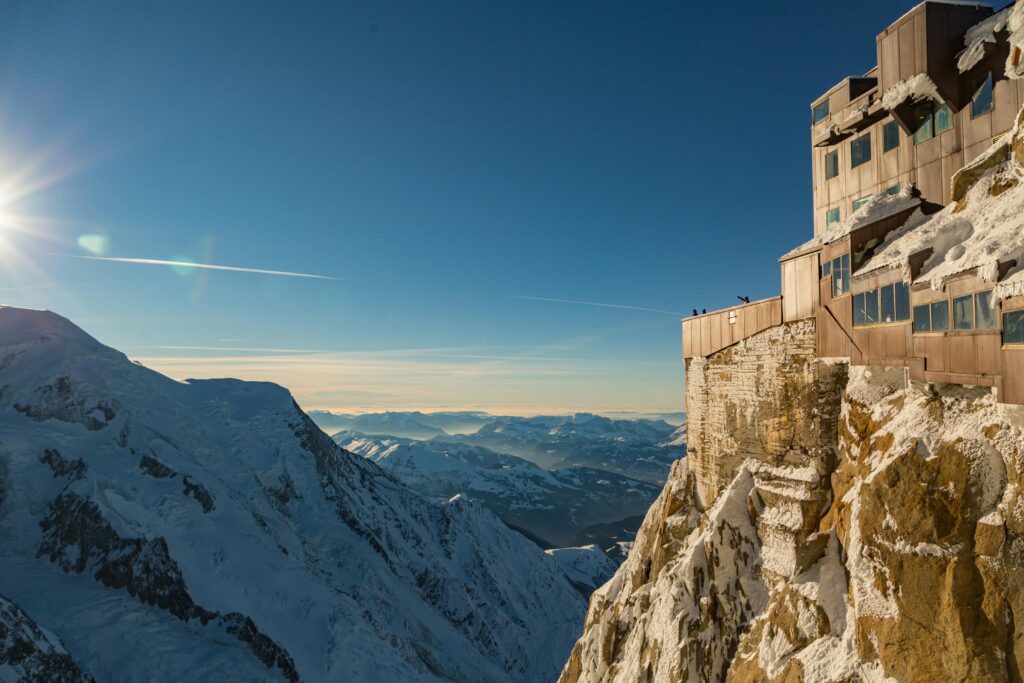 pexels-photo-1789489-1789489 Breathtaking winter view of snow-capped mountains and a building perched on a cliff edge.