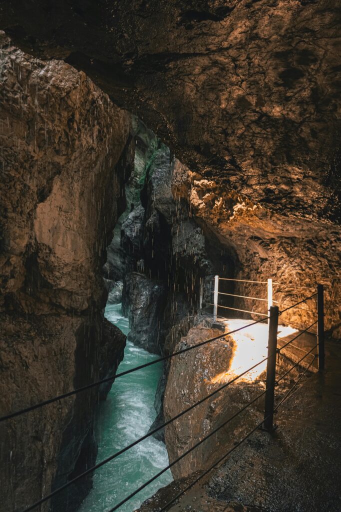Explore the rocky gorge walkway in Garmisch-Partenkirchen, Germany, featuring flowing water and textured cave walls.