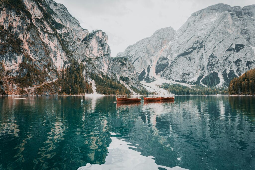 Tranquil lake scene with boats and mountain backdrop in Trentino-Südtirol, Italy.