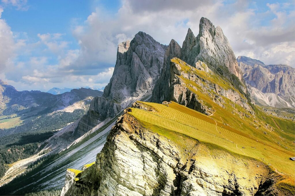 A breathtaking view of jagged mountain peaks and lush valleys under a vibrant blue sky.